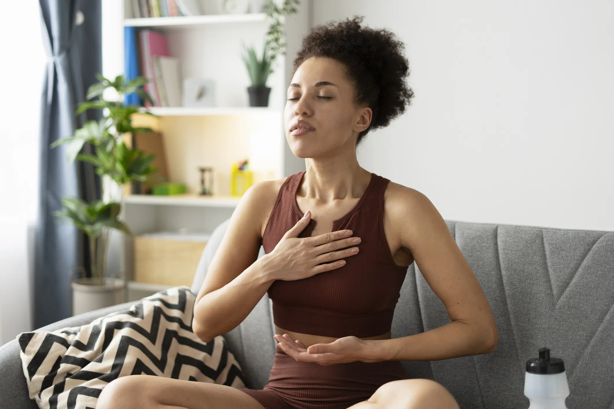A woman practicing deep breathing exercises at home.