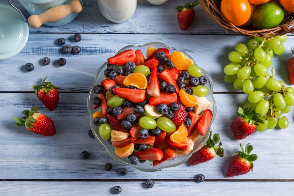 A colorful fruit salad with strawberries, blueberries, grapes, and kiwi.