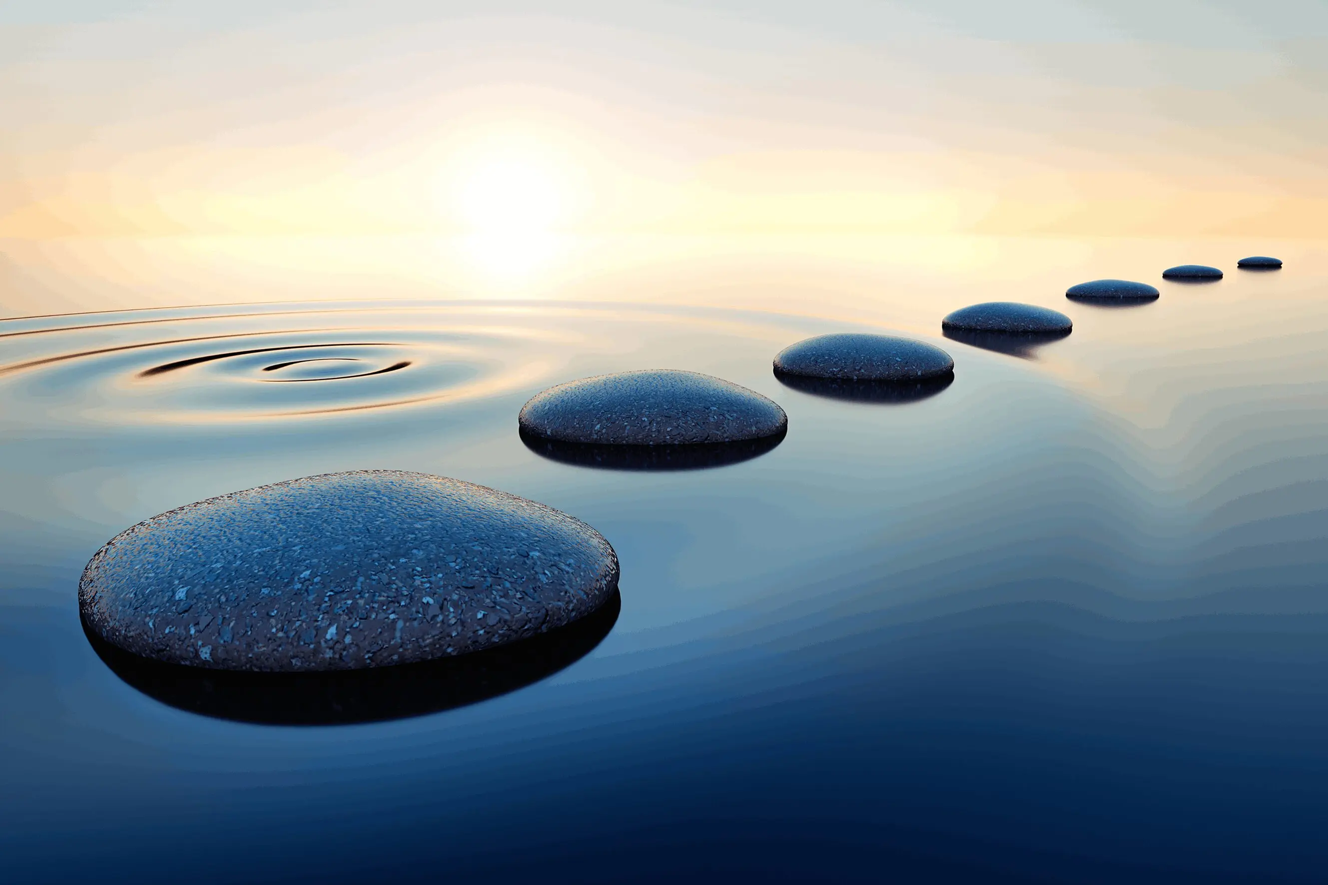 Smooth stepping stones over calm water at sunset.