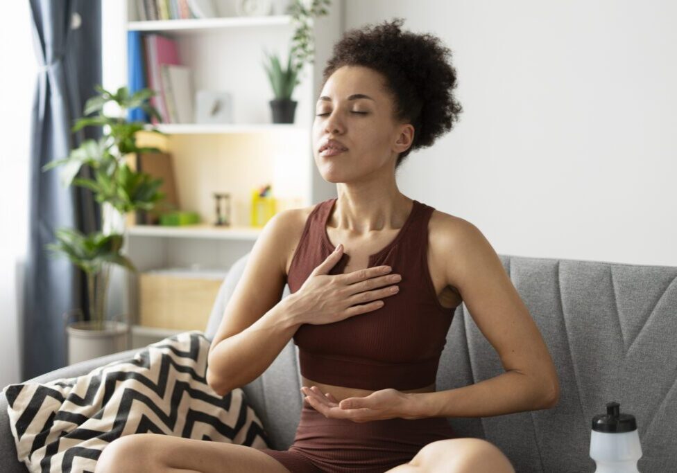 A woman practicing deep breathing exercises at home.